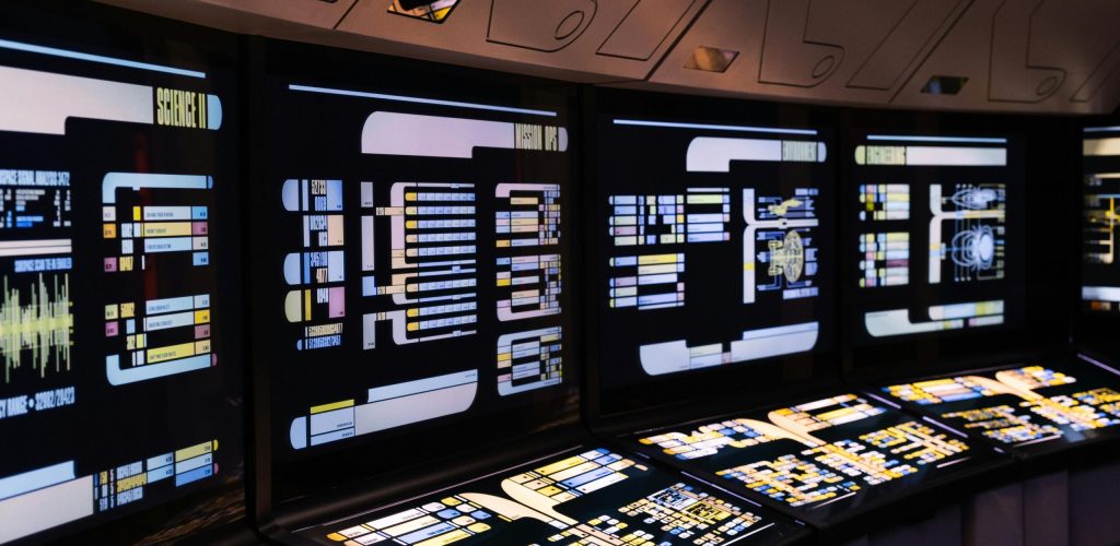 A high-tech command center with illuminated digital screens in a futuristic setting.